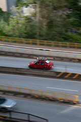 Obraz premium Red Fiat Siena side profile in motion, Compact work sedan driving on city avenue