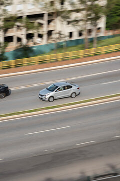 Silver Fiat Cronos high angle in motion, Compact family sedan driving on city avenue