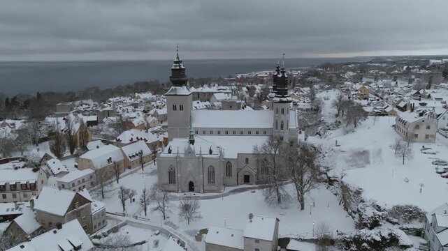 Aerial Orbit of Snow-covered Visby Cathedral (Domkyrka) in Winter with Baltic Sea in the Background, Gotland Sweden
