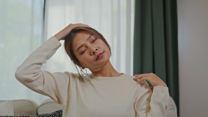 Fototapeta premium Asian woman stretching her neck on sofa at home