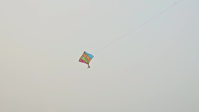 A colorful kite flying in the Blue Sky During Sunny Day . It is an Outdoor Activity.