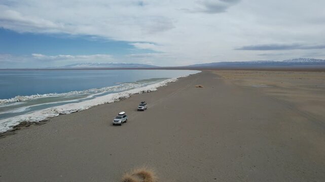 Traveling New Horizons. Journey Along Icy Coast. Expedition Travels Beside Frozen Shoreline Into Unknown. Convoy Advances Along Cold Desert Coast Seeking Distant Horizons And Adventure