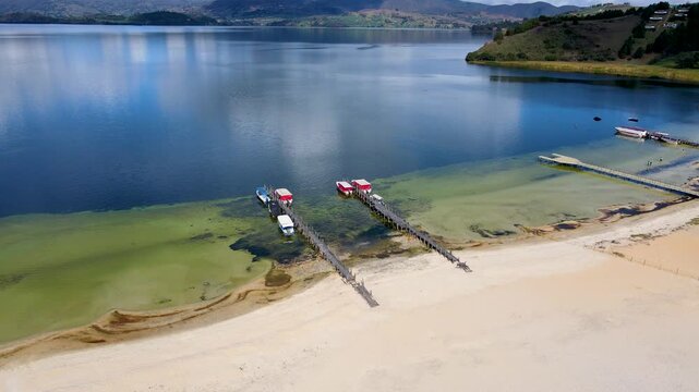 A stunning view of Tota Lagoon showcasing red fishing boats and clear waters under a blue sky, with sandy shores visible.