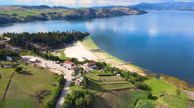 Stunning aerial view of Tota Lagoon showing clear blue waters, green hills, and sandy beaches under a bright sky.