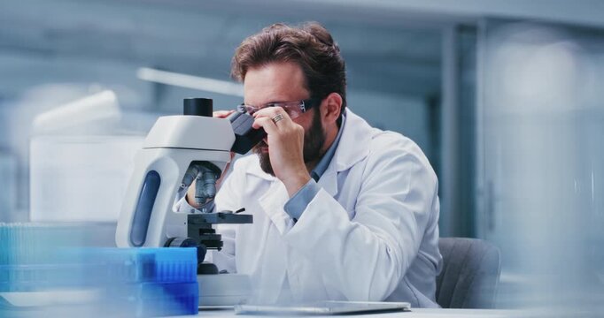 Microscope, research and science with man in laboratory for development or investigation. Analysis, goggles and medical sample with professional scientist at work on clinical trial or experiment