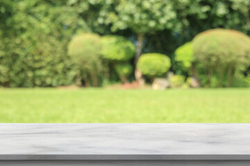 Fototapeta premium Empty marble table top with abstract blur green park garden background