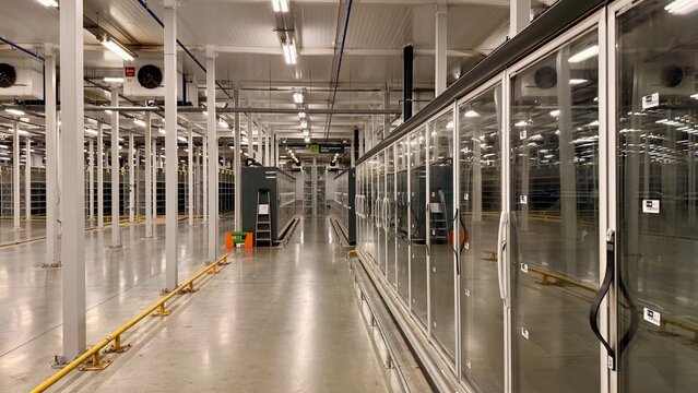 Modern data center interior with rows of server racks and cooling systems. High-tech cloud computing infrastructure room. Large enterprise network hardware, digital database storage warehouse.