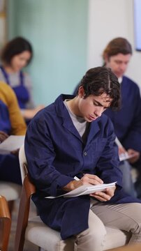 In lecture, young man employee writes on large piece of paper, fills out questionnaire, answers exam questions. Professional aptitude, identification of initiative and talented employees