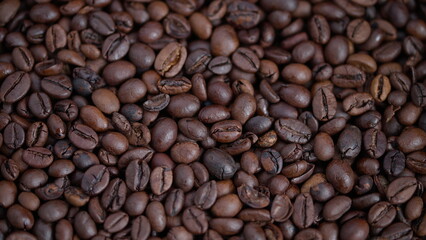 Fototapeta premium Closeup of glossy roasted beans with textured appearance and rich tones, Magnified image of shiny roasted coffee beans showing diversity in shapes and tactile surface features