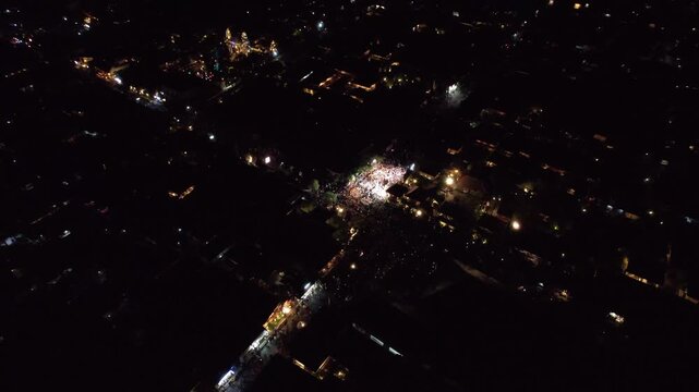 Wide aerial panorama revealing detailed demon sculptures moving through village streets at dusk. Sunset Over Ogoh-Ogoh Festival.