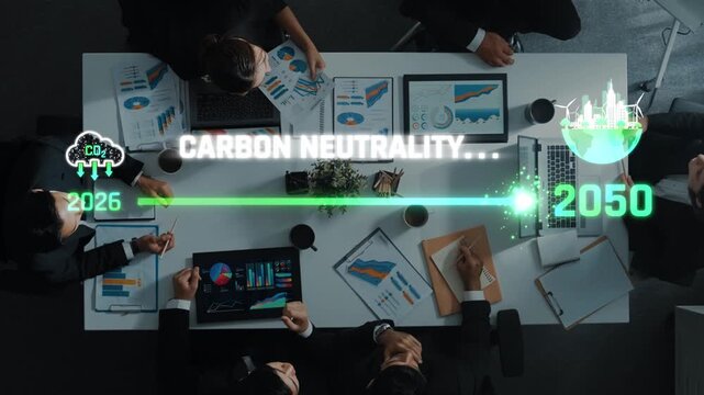 High-angle view of a business team discussing carbon neutrality goals, showcasing laptops, charts, and digital tools in a collaborative office environment. Raster