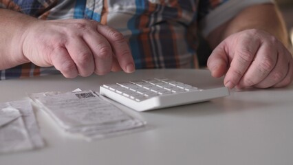 Person using a number pad at a table with receipts and a check nearby in an indoor setting during day time © bisonov