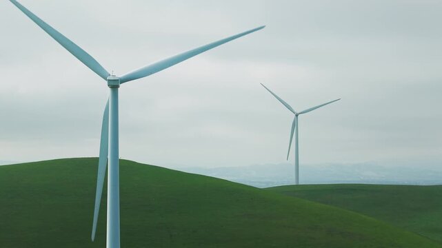 A drone captures a close up of a wind turbine near Altamont Pass in Dublin, California, revealing the scale of its tower and the steady rotation of blades against the open sky