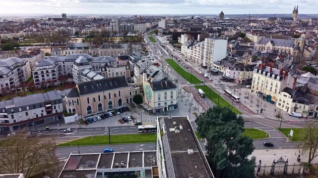Drone flying along Boulevard Mar&eacute;chal Foch in Angers, passing above the vegetated tramway line with cars, residential buildings and urban traffic.
