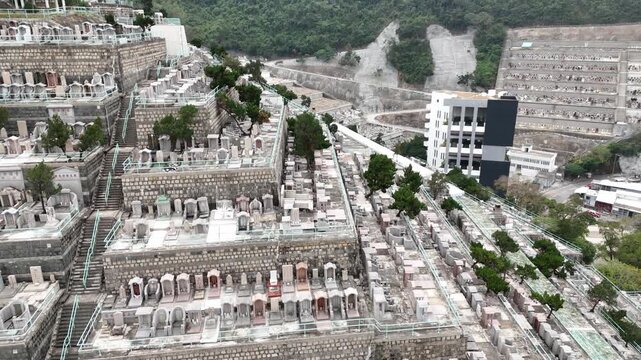 Drone aerial capturing Pok Fu Lam Cemetery in Hong Kong, with hillside tombs, lush greenery, and panoramic cityscape in a tranquil and scenic setting.