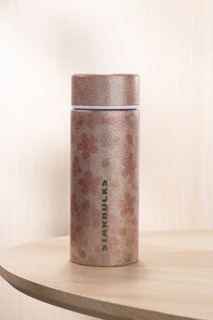 A pink glitter Starbucks limited edition stainless steel tumbler displayed on a wooden table, highlighting sparkling finish and collectible seasonal merchandise.