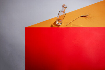 Abstract still life with colored objects, a bottle, and an ear of wheat