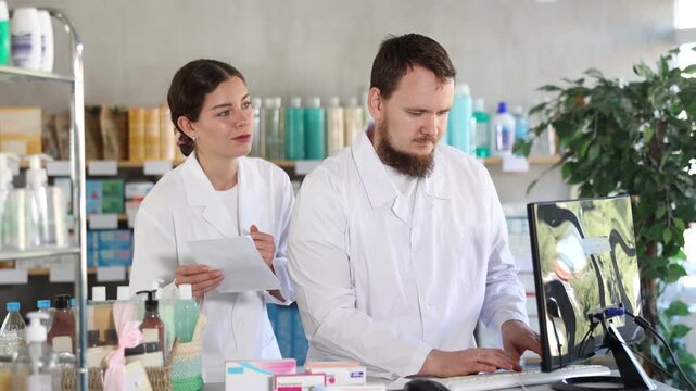 Qualified male and female pharmacists work at a computer, renew stocks in the warehouse, enter new arrivals of medicines and pills. Pharmacists working behind the counter in a pharmacy. High quality