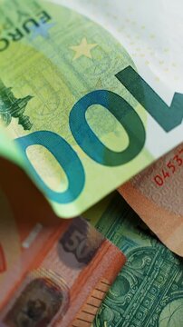 Vertical macro shot of a 100 euro banknote with shallow depth of field as the camera moves across security details, creating a clean finance background for economy and budgeting concepts.