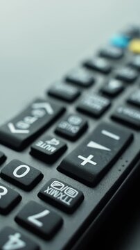 Vertical macro shot of a TV remote with a red power icon button in the foreground, shallow depth of field and soft bokeh&mdash;perfect for tech control, UI, and entertainment concepts.