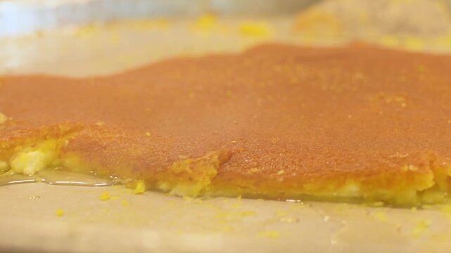 Close up kunafa dessert being served in paper plate with hot sugar syrup poured from metal bowl street sweets shop food preparation close up