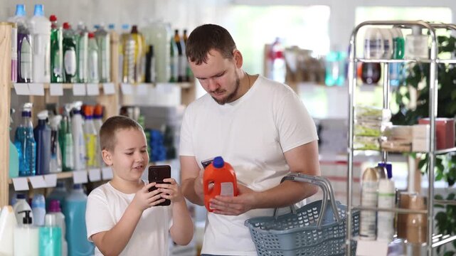Young man with his son buyers scanning qr code for unclogging gel in household chemicals store
