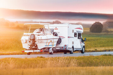 Holiday motorhome carrying boat in green landscape © AlexGo