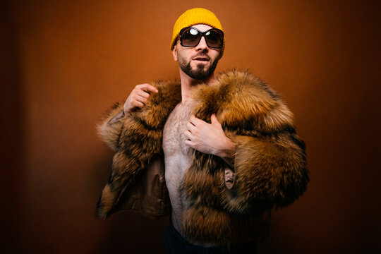 Man posing with furry jacket yellow beanie sunglasses
