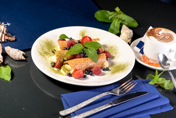 Elegant dessert with cream-filled pastries, fresh berries, and mint