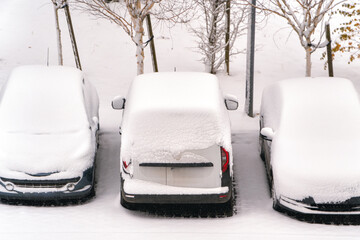 Heavy snowfall covering cars in outdoor lot