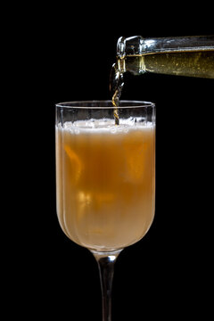 Gourde de bi&egrave;re versant un liquide dor&eacute; p&eacute;tillant dans un verre de cocktail &eacute;l&eacute;gant, sur fond noir.