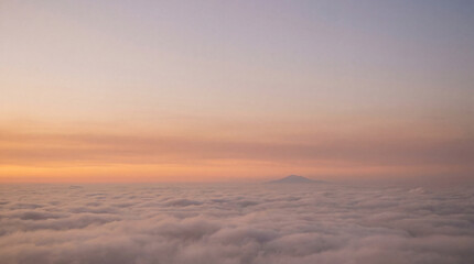 Obraz premium Scenic mountain peak rising above a soft sea of clouds at sunrise