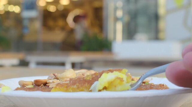 Jordan kunafa dessert close up in paper plate with sugar syrup melted cheese pistachio cashew topping spoon bokeh cafe background