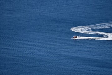 Naklejka premium Seascape with scenic view of a young couple on a jet ski cruising on the waters of Therasia island in Cyclades, South Aegean Greece.