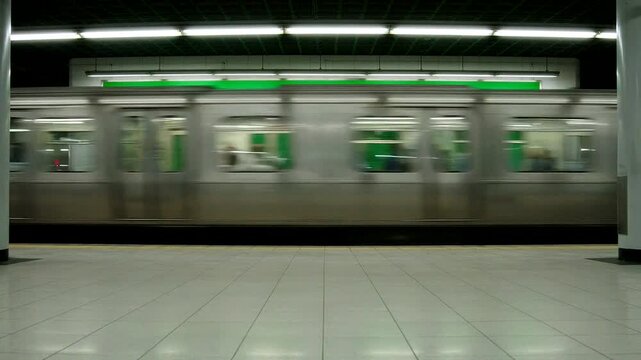Blank green billboard at an underground subway station with a moving train and tiled platform floor.