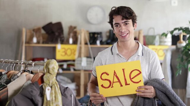 Guy with poster in hands announces discounts. Closing of season and price reduction in clothing store, closing of season, record price reduction, liquidation of collection 