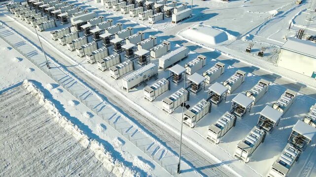 Wide diagonal drone flight revealing full 100MW Kiisa battery park with substation and grid infrastructure during sunny winter in Estonia.