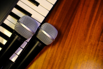 Obraz premium Microphones on piano keyboard with wooden background, music and singing concept.