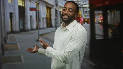 Fotobehang Londen rode bus Man standing and smiling, visible face and white shirt on city street beside a red doubledecker bus with blurred building backdrop  urban confidence.  © Krakenimages.com