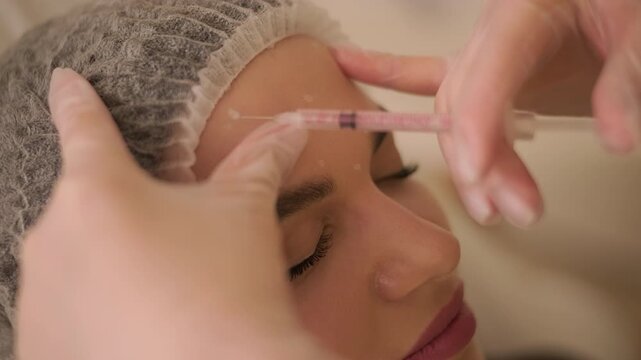 Professional doctor giving botulinum toxin injection in female patient's face.
