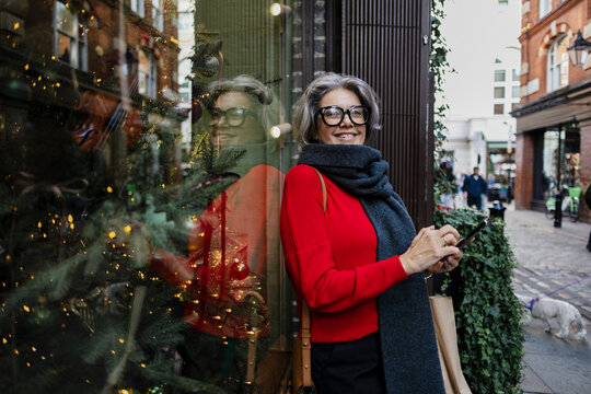 Smiling woman with glasses shopping on city street at Christmas time