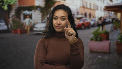 Woman with hand on chin and hoop earring on a cobblestone street beside potted planters and parked cars wearing brown turtleneck  thoughtful confidence. © Krakenimages.com