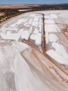 Aerial view of the stark white salt pans contrasting with the reddish-brown earth and the distant blue sky, Old Chandler Potash Mine Site, Western Australia, Australia.