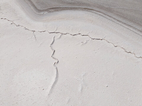 Aerial view of cracked earth revealing stark contrasts between light and dark sediments at the Old Chandler Potash Mine Site, Old Chandler, Western Australia, Australia.