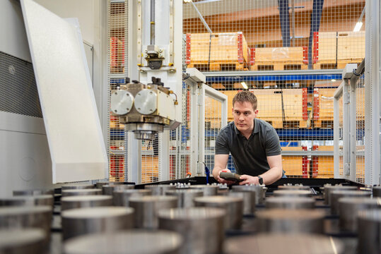 Employee inspecting metal components in modern industrial factory