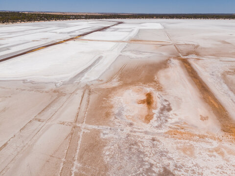 Aerial view of the stark, arid landscape marked by geometric patterns, contrasting white salt flats with earthy brown tones, Old Chandler Potash Mine Site, Western Australia, Australia.