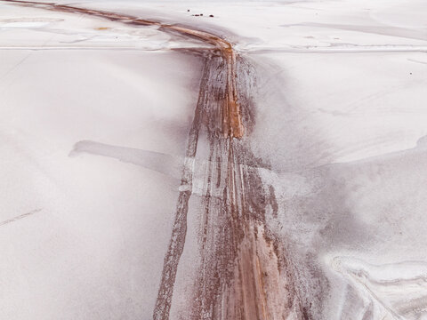 Aerial view of a desolate landscape where stark white salt flats meet rusty streams, creating an otherworldly spectacle, Old Chandler Potash Mine Site, Western Australia, Australia.
