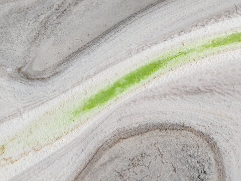 Aerial view of the bright green algae contrasting against the pale, cracked earth at the Old Chandler Potash Mine Site, Chandler, Western Australia, Australia.