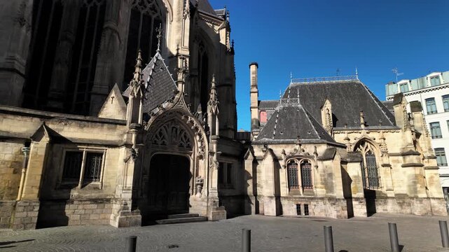 Tilt down view of Saint Maurice Church in Lille, showcasing Gothic facade and historic stone detail under clear blue sky.