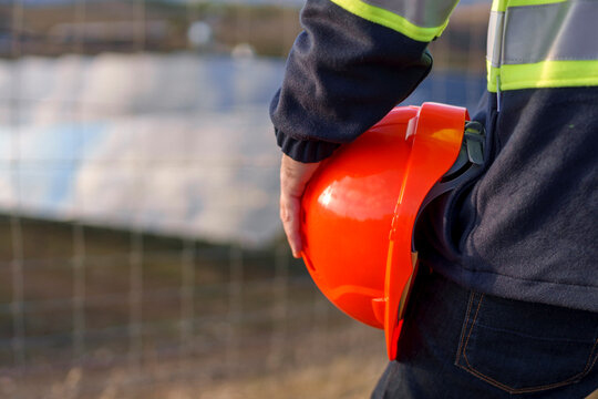 Engineer holding hard hat at solar panel site on sunny day
